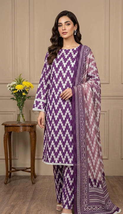 Woman wearing a purple and white patterned outfit in a room with a wooden table and flowers.