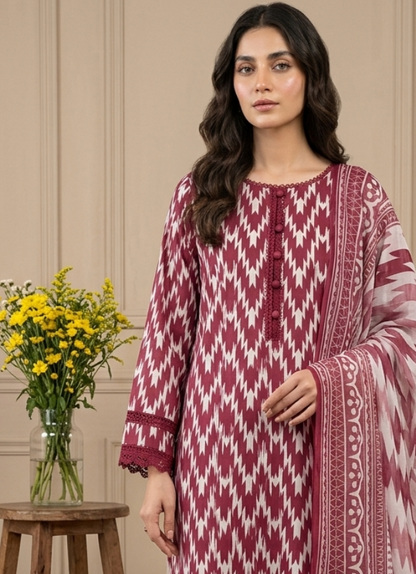 Woman wearing a maroon and white patterned outfit standing in a room with wooden floor and beige walls.