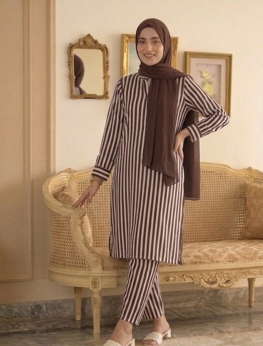 Woman in a striped outfit with a hijab standing in a decorated room.