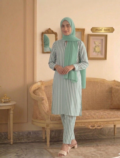 Woman wearing a green hijab and striped outfit in a room with a couch and decorative items.