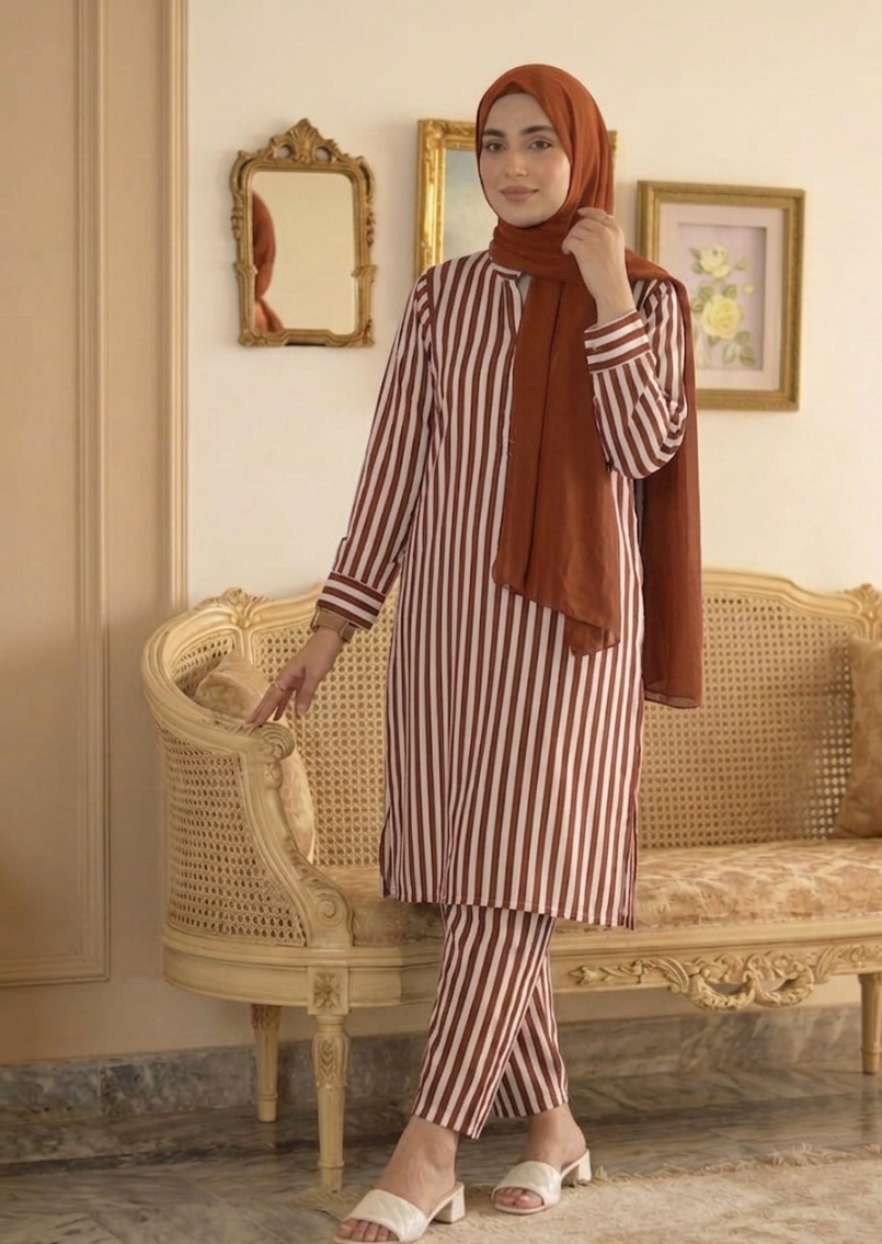 Woman in a striped outfit with a hijab standing in an elegant room.