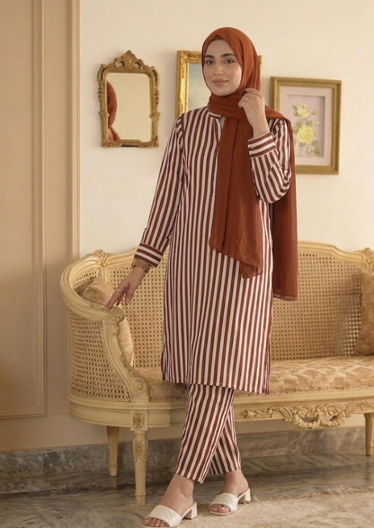 Woman in a striped outfit with a hijab standing in an elegant room.