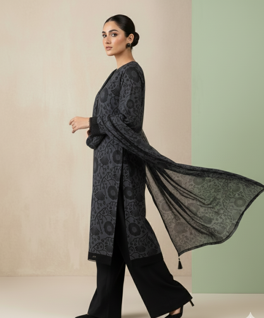 Woman wearing a long, dark patterned coat against a light background