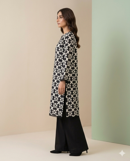 Woman wearing a black and white patterned long shirt with black pants against a beige and green background